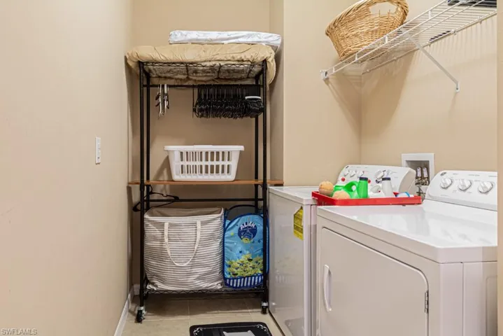 Laundry area with light tile patterned floors and washer and clothes dryer