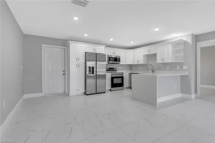Kitchen featuring stainless steel appliances, kitchen peninsula, sink, and white cabinets