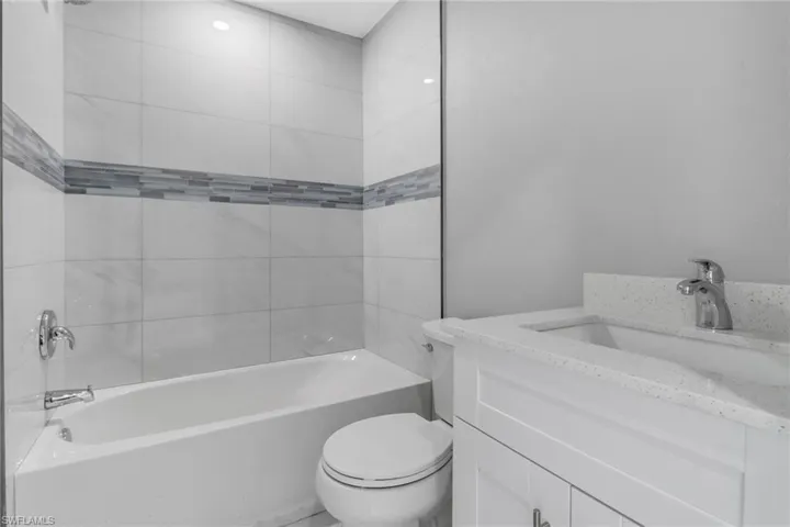 Full bathroom with vanity, tiled shower / bath, and toilet