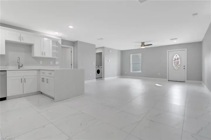 Kitchen featuring washer / clothes dryer, white cabinetry, dishwasher, sink, and ceiling fan