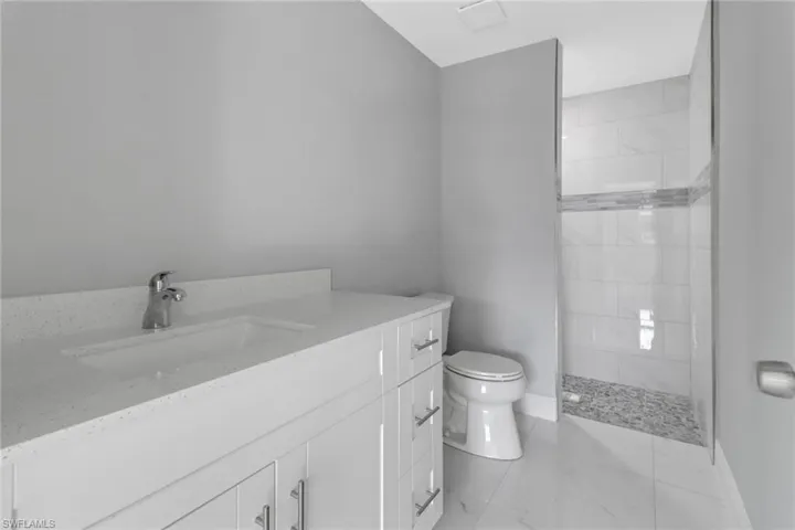 Bathroom with vanity, a tile shower, and toilet