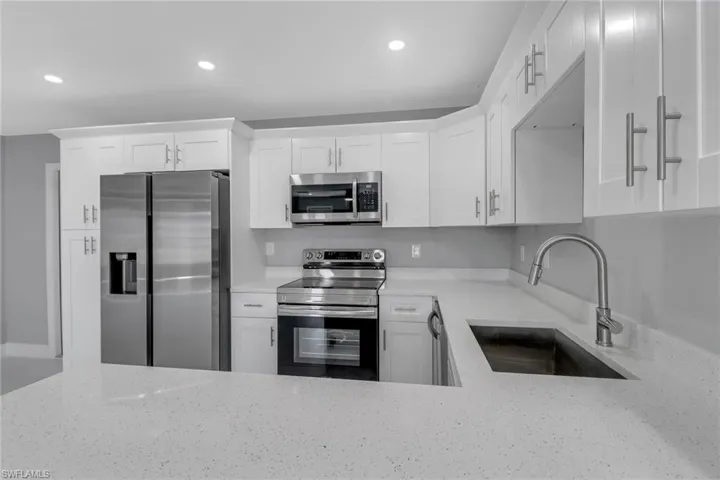 Kitchen with appliances with stainless steel finishes, sink, and white cabinets