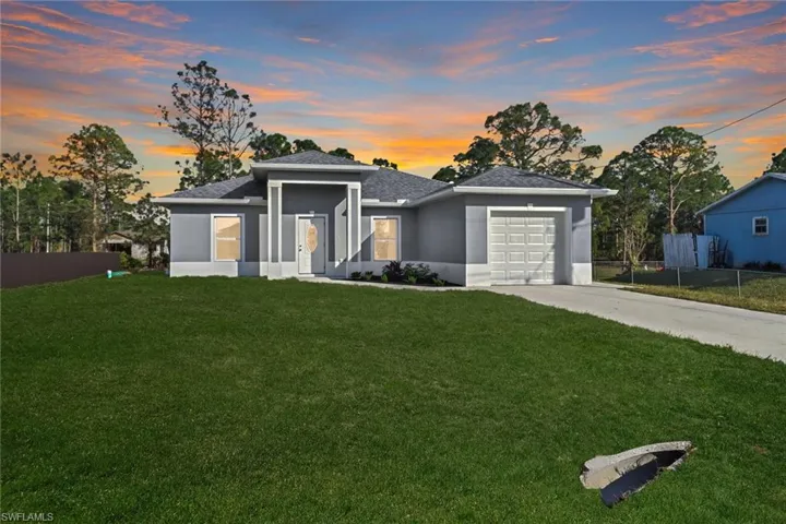 View of front of home featuring a yard, stucco siding, concrete driveway, an attached garage, and fence