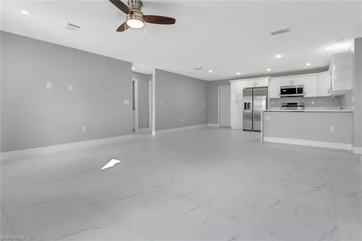 Unfurnished living room featuring sink and ceiling fan