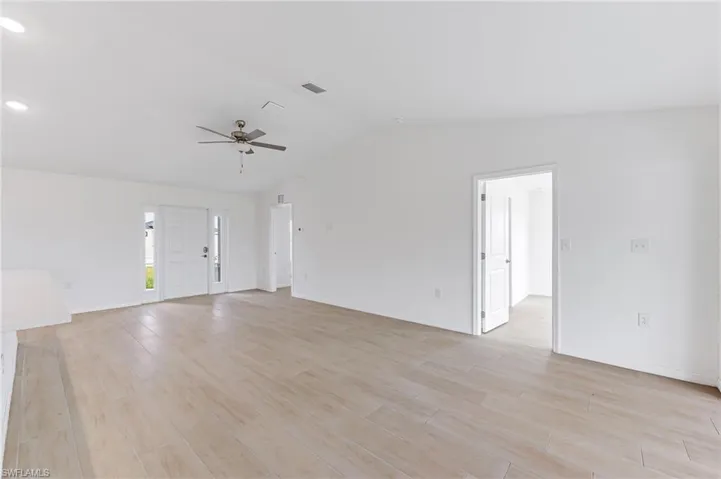 Unfurnished living room featuring lofted ceiling, ceiling fan, visible vents, baseboards, and light wood finished floors
