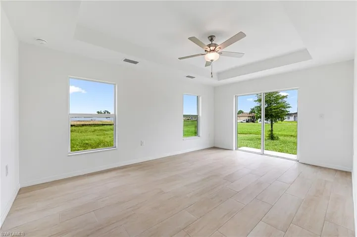 Spare room with a raised ceiling, visible vents, baseboards, and light wood finished floors