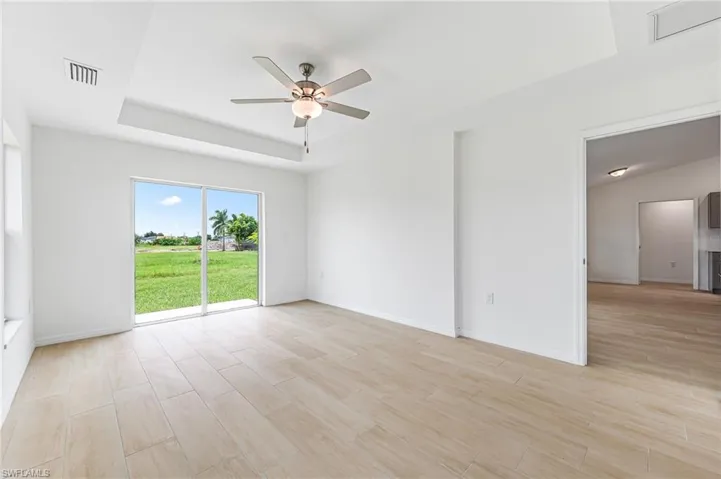Unfurnished room featuring visible vents, a raised ceiling, baseboards, ceiling fan, and light wood-type flooring