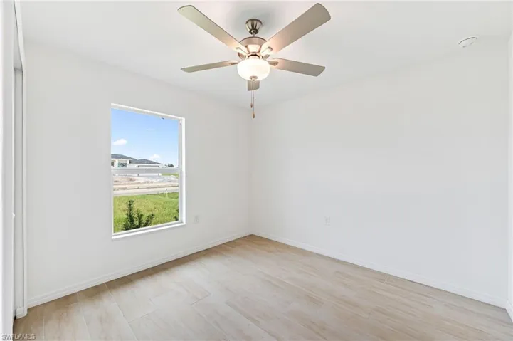 Unfurnished room featuring light wood finished floors, ceiling fan, and baseboards
