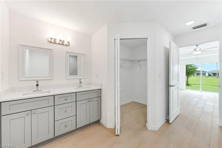 Bathroom with baseboards, a spacious closet, visible vents, and a sink