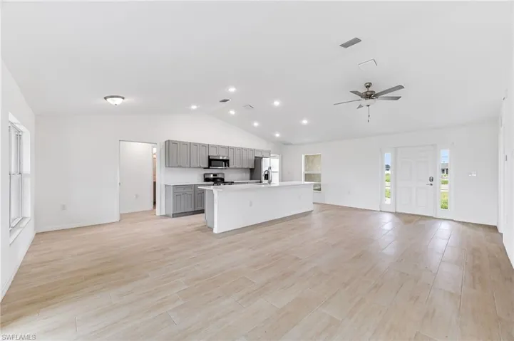 Kitchen featuring appliances with stainless steel finishes, open floor plan, a kitchen island with sink, and gray cabinetry