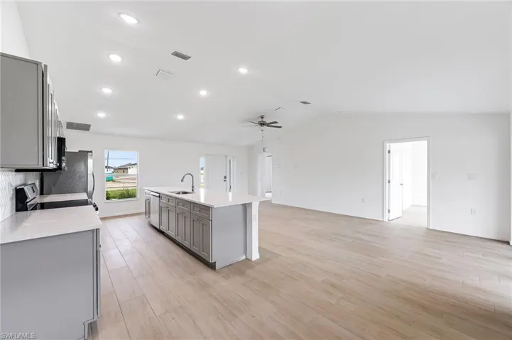 Kitchen with lofted ceiling, light wood-style flooring, a sink, light countertops, and gray cabinets