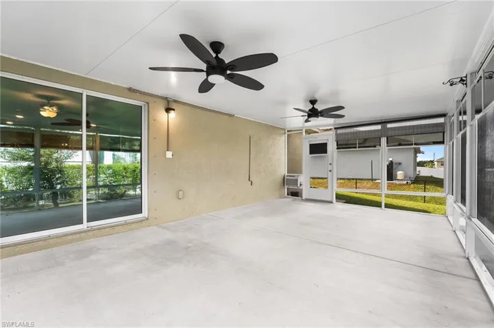 Unfurnished sunroom featuring an AC wall unit, ceiling fan, and a healthy amount of sunlight