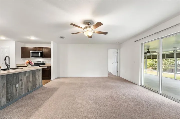 Unfurnished living room featuring light carpet and sink
