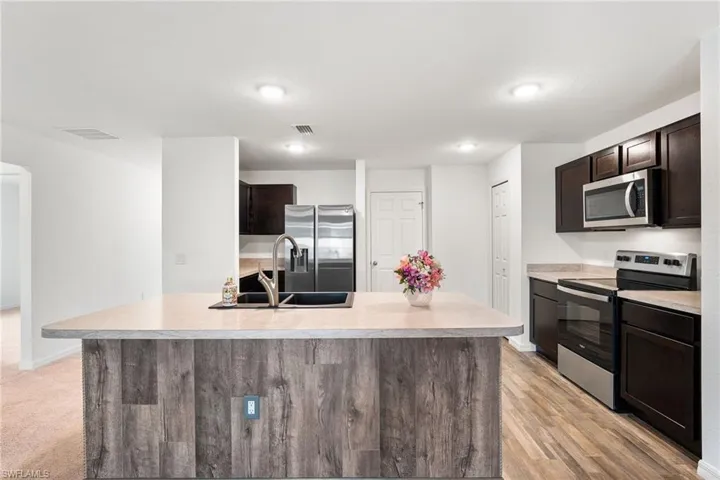 Kitchen with a center island with sink, dark brown cabinets, sink, and stainless steel appliances