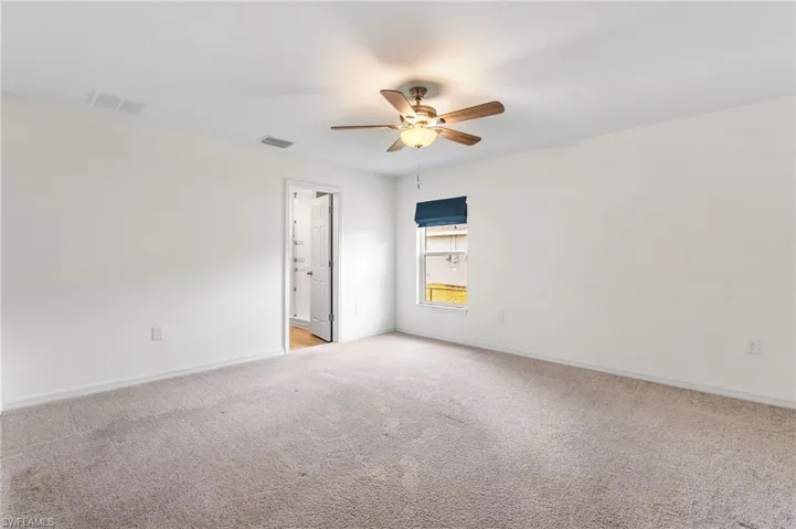 Carpeted empty room featuring ceiling fan