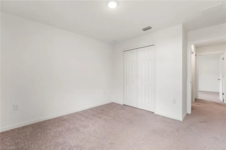 Unfurnished bedroom featuring light colored carpet and a closet