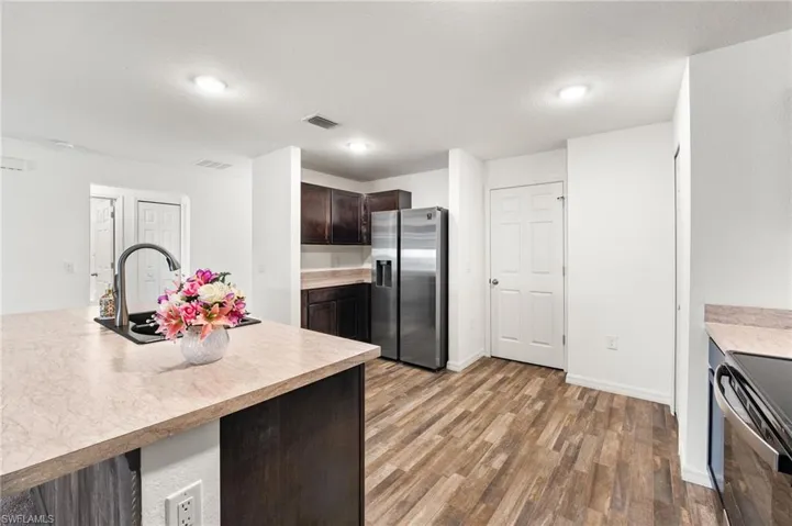Kitchen featuring stainless steel fridge, stove, dark brown cabinetry, sink, and hardwood / wood-style flooring