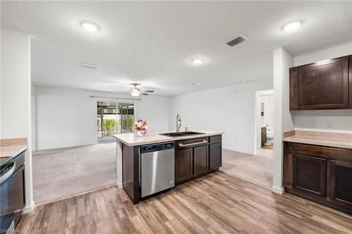 Kitchen with dishwasher, light wood-type flooring, dark brown cabinets, and sink