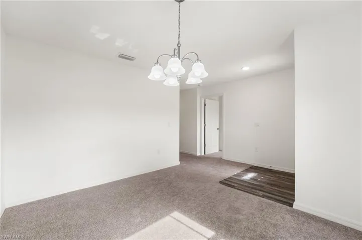 Unfurnished room featuring carpet flooring and an inviting chandelier