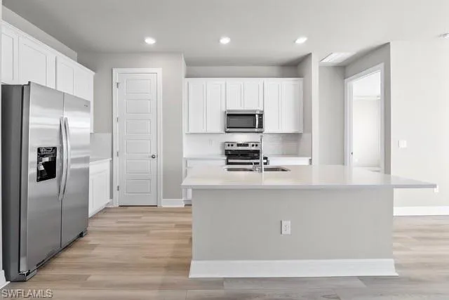 Kitchen featuring white cabinets, stainless steel appliances, and a kitchen island with sink