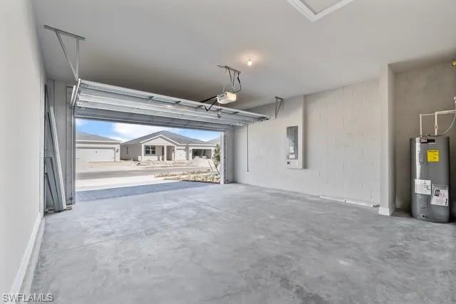 Garage featuring electric panel, water heater, and a garage door opener