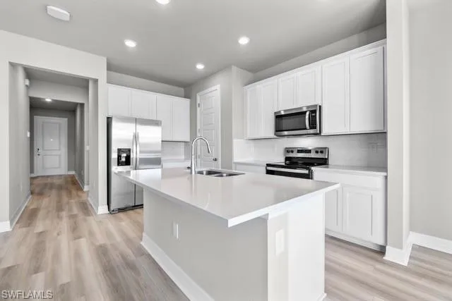 Kitchen with sink, white cabinetry, an island with sink, and appliances with stainless steel finishes