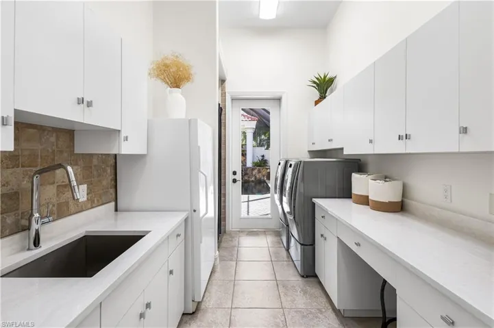 Laundry Room with Courtyard access and a Multi-purpose Walk In Shower. LG Washer and Dryer and a Amana Deep Freeze Freezer. Cambria Quartz countertops, Single Sink, Cabinetry and Linen closet.