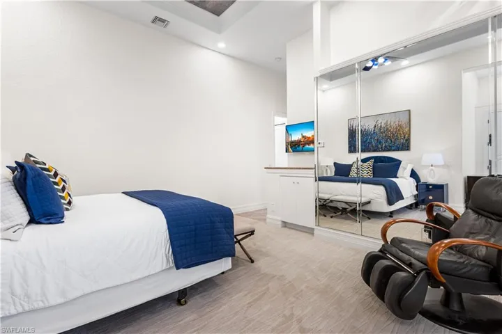 2nd Ensuite Bedroom with Double French Doors leading to the Courtyard. Coffered Ceiling, Transom Window, Carpet, Mirrored Wall and Closet. Built In TV Electronics Cabinet with a Cambria Quartz countertop.