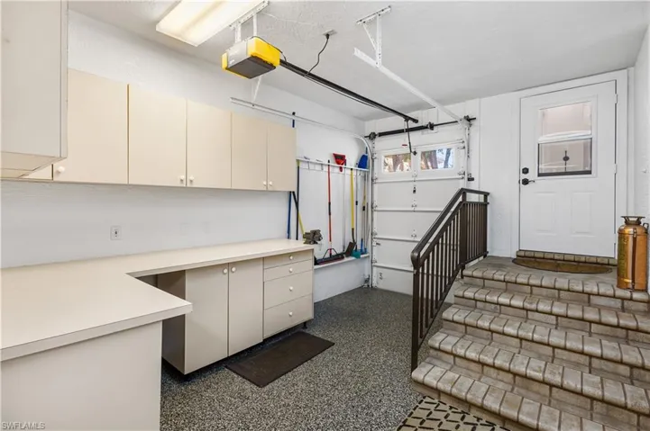 thisis the other part of the garage. Additional Back Entrance Garage Bay For a Golf Cart or Water Toys! Work Bench Area with Solid Countertops, Cabinetry and a Walk In Storage Closet!