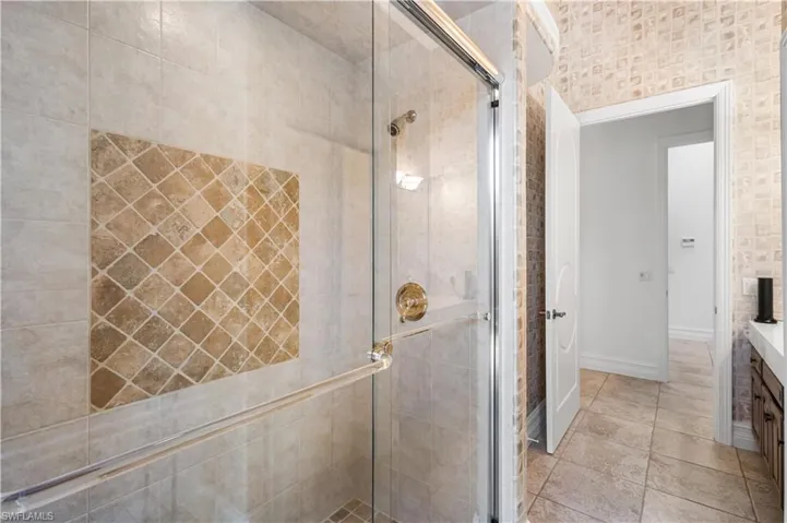 2nd Bedroom Ensuite features a Walk In shower with Tumbled Marble Tile, Single Vanity Cambria Quartz countertop with Cabinetry, Linen Closet and Courtyard access.