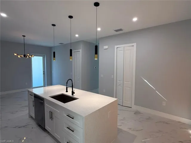 Kitchen featuring hanging light fixtures, light stone counters, white cabinets, dishwasher, and recessed lighting