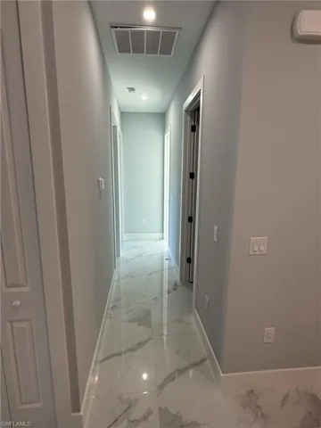 Hall with light marble finish floors, a wall mounted air conditioner, and recessed lighting