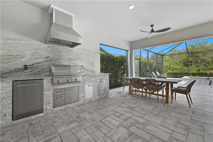 View of patio / terrace with an outdoor kitchen, a sunroom, a ceiling fan, an in-ground hot tub, and outdoor dining area
