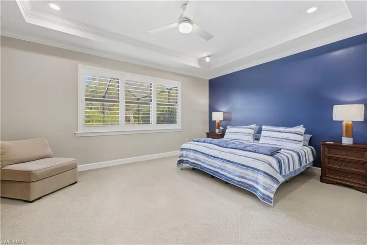 Carpeted bedroom featuring a raised ceiling, crown molding, a ceiling fan, and recessed lighting
