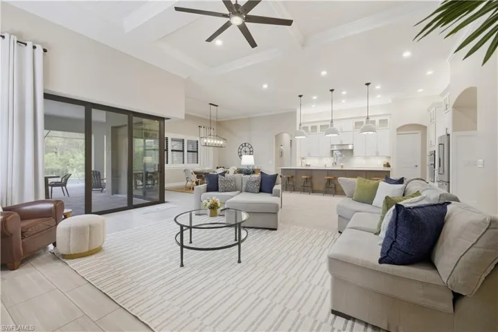 Living area featuring arched walkways, beamed ceiling, coffered ceiling, recessed lighting, and ceiling fan