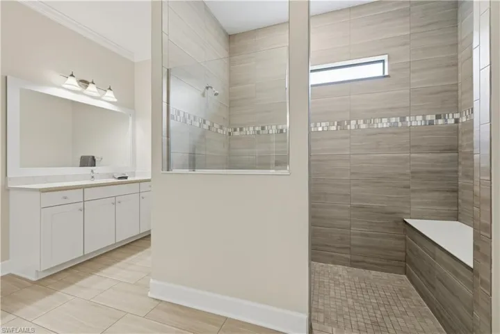 Full bathroom featuring vanity, walk in shower, and ornamental molding