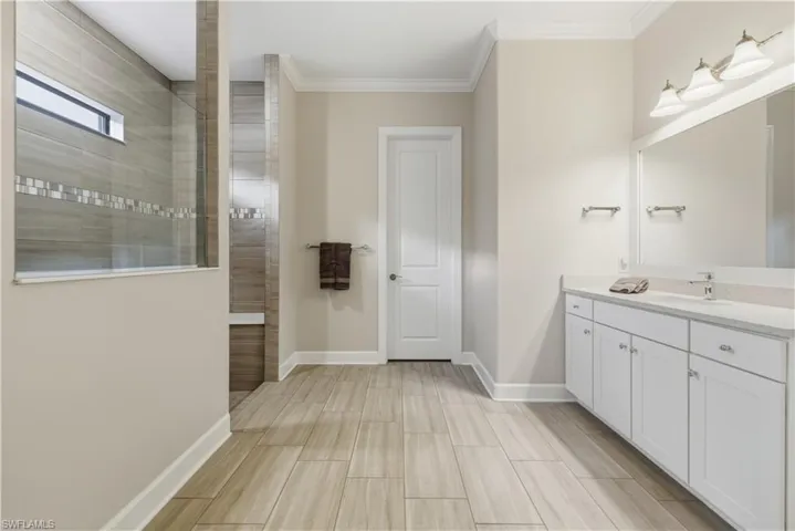 Bathroom with vanity, walk in shower, ornamental molding, and wood finish floors