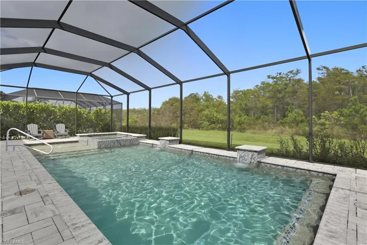 View of swimming pool featuring a lanai, a sunroom, and a pool with connected hot tub