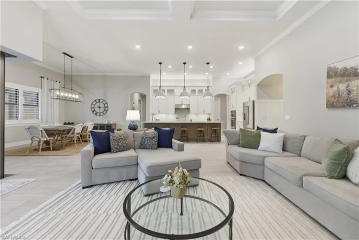 Living area with arched walkways, ornamental molding, recessed lighting, and a chandelier