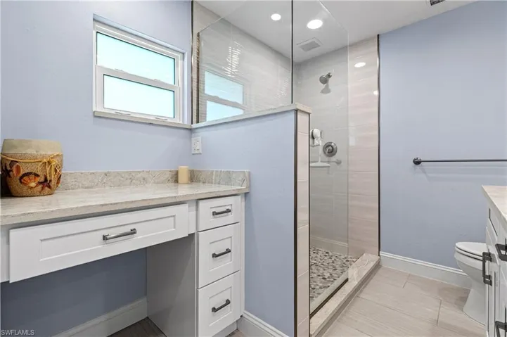 Bathroom featuring vanity, walk in shower, and recessed lighting