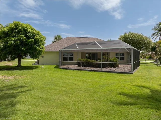 Back of property with a lawn, glass enclosure, and a patio