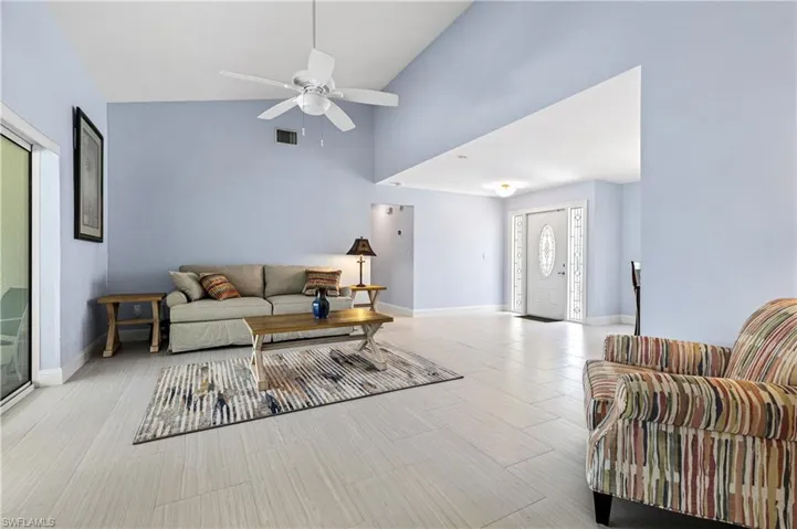 Living room with ceiling fan and high vaulted ceiling