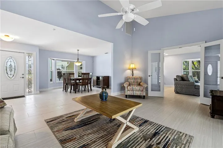 Living room featuring french doors, ceiling fan, and a towering ceiling