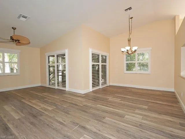 Unfurnished room with lofted ceiling, a ceiling fan, light wood-style flooring, and a chandelier