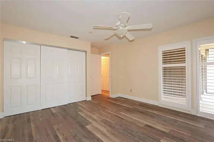 Unfurnished bedroom with a ceiling fan, dark wood-style floors, and a closet