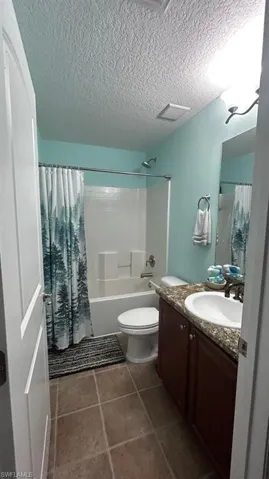 Bathroom featuring a bathtub with shower, toilet, and vanity with an integrated sink