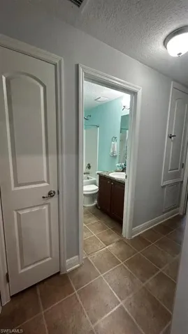 Full bathroom featuring a dark wood vanity with a granite-style countertop, a white toilet, and a bathtub with shower