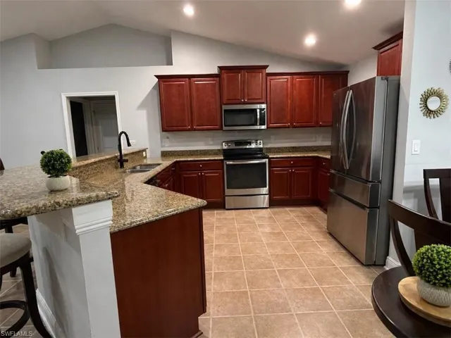 Kitchen featuring wood cabinetry, stainless steel appliances, granite countertops, and a tile backsplash