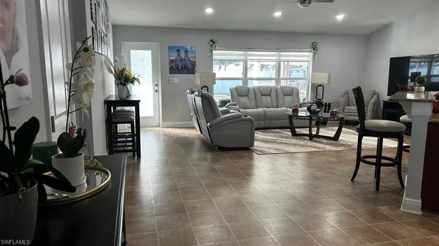 Open-concept living area featuring neutral-toned tile flooring, recessed lighting, and a ceiling fan