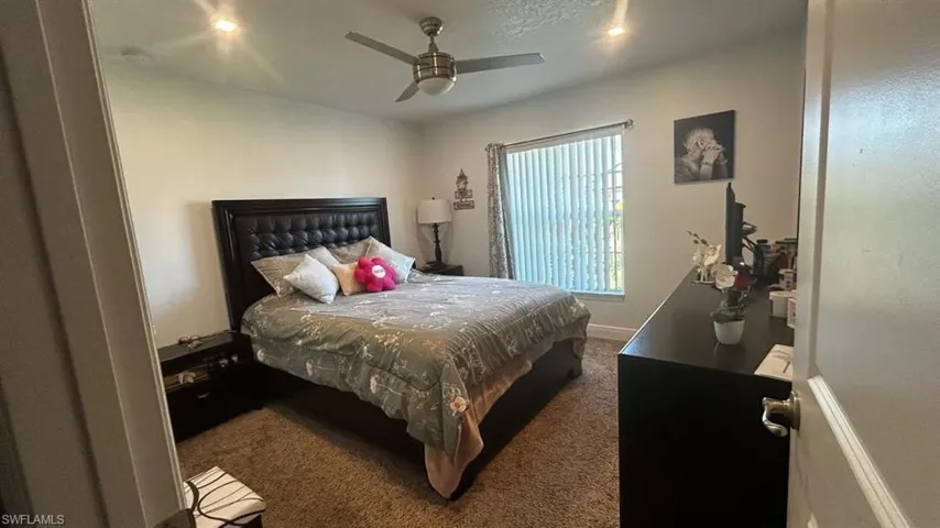 Carpeted room featuring a ceiling fan with integrated lighting, recessed lighting fixtures, and a window with vertical blinds